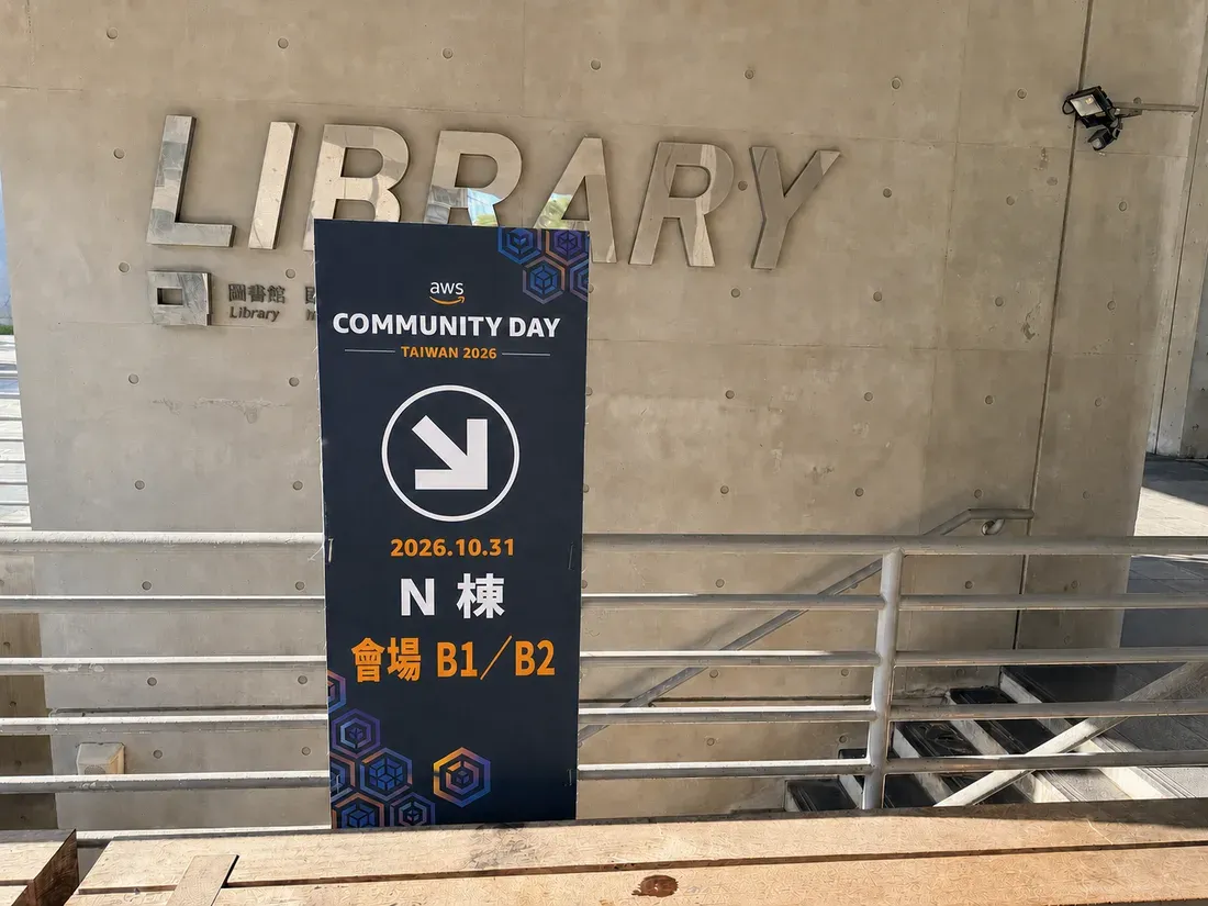 當天的會場指示牌樣張，立在 N 棟中庭的 LIBRARY 牆面，箭頭指向下樓的樓梯